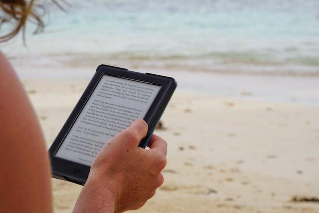 Persona leyendo un Kindle en la playa